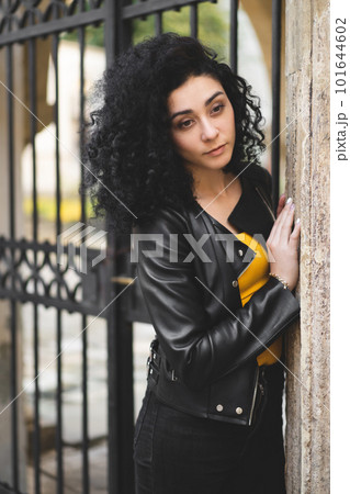 a beautiful girl in a leather jacket poses against the background of the city. 101644602