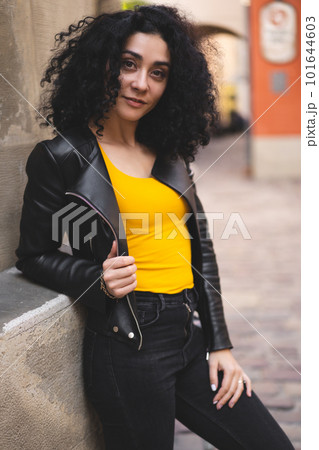a beautiful girl in a leather jacket poses against the background of the city. 101644603
