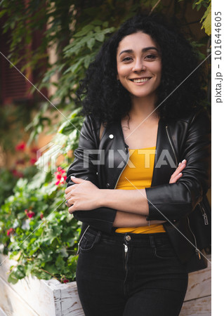 a beautiful girl in a leather jacket poses against the background of the city. 101644605