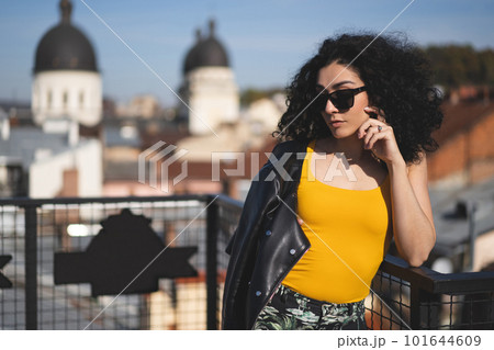 a beautiful girl in a leather jacket poses against the background of the city. 101644609