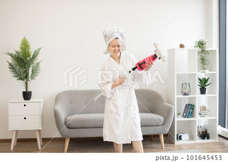 Housewife imitating guitar player with stick vacuum at home 101645453
