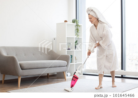 Woman cleaning carpet in living room with cordless vacuum Woman cleaning carpet in living room with cordless vacuum 101645466