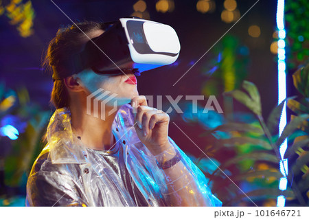 pensive stylish woman in metaverse in vr goggles 101646721