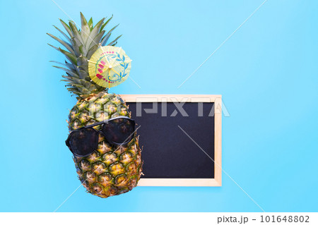 Pineapple in sunglasses with empty blackboard for your text on blue background Pineapple in sunglasses with empty blackboard for your text on blue background 101648802