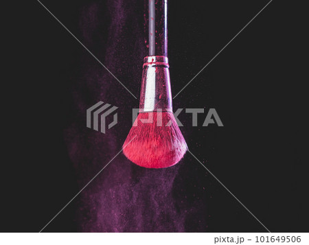 Make-up brush with pink powder splashes explosion on black background. Beauty concept 101649506