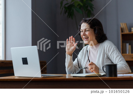 Happy middle aged senior woman sit with laptop talk on video call with friends family. Laughing mature old senior grandmother having fun talking speaking with grown up children online Happy middle aged senior woman sit with laptop talk on video call with friends family. Laughing mature old senior grandmother having fun talking speaking with grown up children online 101650126