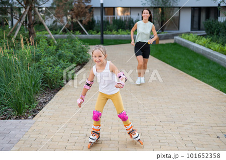 A little girl and her mom do a bridge exercise at the outdoor sports ground.  101652358