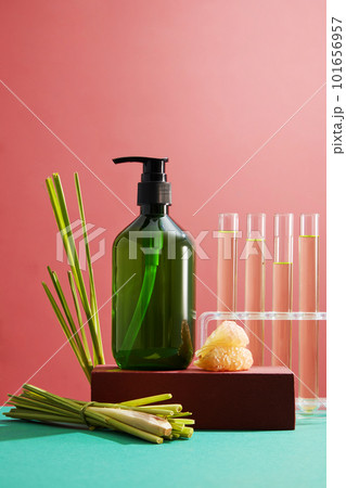 Abstract minimalist scene - empty bottle on podium, fresh lemongrass and test tube containing pink grapefruit essence on pink background. Mockup for cosmetics with ingredients extracted. Abstract minimalist scene - empty bottle on podium, fresh lemongrass and test tube containing pink grapefruit essence on pink background. Mockup for cosmetics with ingredients extracted. 101656957