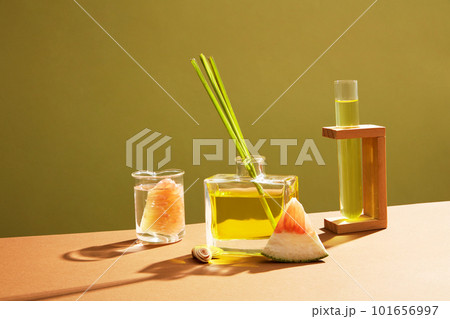 Transparent glass bottle full filled with essential oil extracted from pink pomelo (Citrus maxima) and lemongrass. Empty label for cosmetic product mockup Transparent glass bottle full filled with essential oil extracted from pink pomelo (Citrus maxima) and lemongrass. Empty label for cosmetic product mockup 101656997