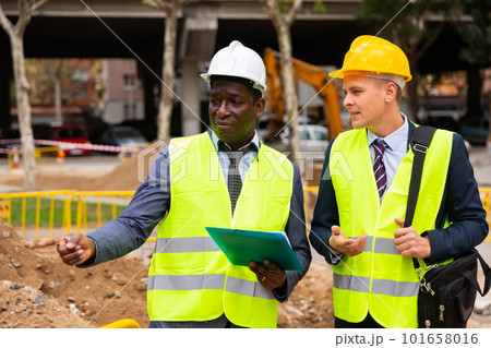 Two men workers discuss the project, holding work documents 101658016