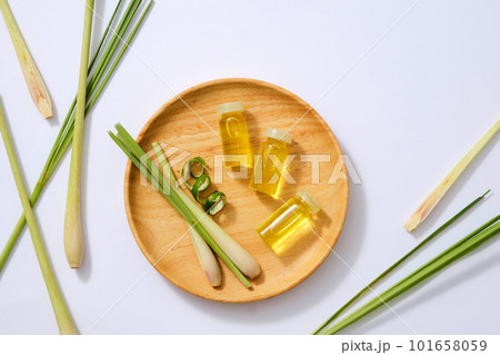 Top view of essential oil bottles on wooden dish and fresh lemongrass on light background. Scene for advertising product of lemongrass essential oil extract. Herbal good for the heart, reduce stress. Top view of essential oil bottles on wooden dish and fresh lemongrass on light background. Scene for advertising product of lemongrass essential oil extract. Herbal good for the heart, reduce stress. 101658059