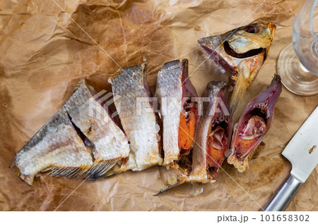 Dried jerked salted fatty bream with caviar, cut into pieces, lies on paper-covered table. Dried jerked salted fatty bream with caviar, cut into pieces, lies on paper-covered table. 101658302