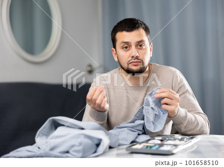 Man sewing button on shirt sleeve at home Man sewing button on shirt sleeve at home 101658510