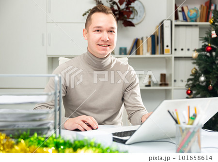 Positive man office worker using laptop during Christmastime 101658614