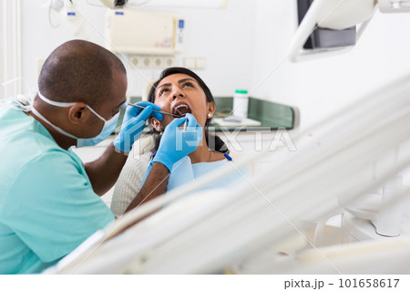Dentist male in uniform is examinating of female in clinic Dentist male in uniform is examinating of female in clinic 101658617