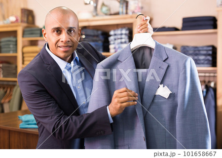 Friendly salesman offering suit in menswear boutique Friendly salesman offering suit in menswear boutique 101658667