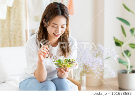 リビングでサラダを食べる若い女性 リビングでサラダを食べる若い女性 101658689