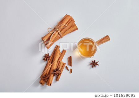 Top view of cinnamon sticks, anise and little glass containing essential oils on white background. Minimal nature scene for cosmetic or product of natural herbal extract. 101659095