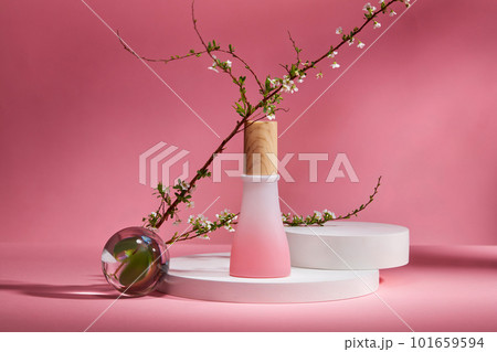 Scene mockup for cosmetic product with empty bottle without label, empty podiums, transparent ball and flower branch on pink background. Space for cosmetic product mockup and display 101659594