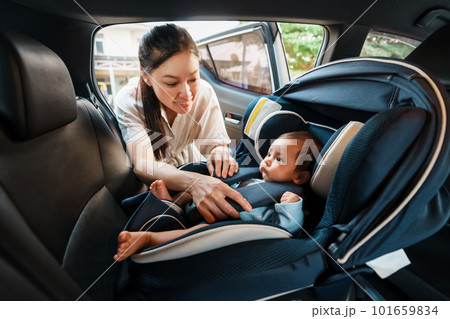 happy mother is fastening safety belt to newborn baby in car seat 101659834