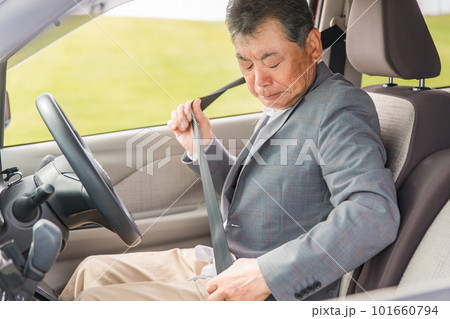 自動車の運転席に乗りシートベルトを締めるアジア人の高齢者ドライバー 101660794