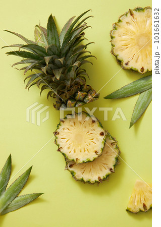 Creative background with fresh pineapple (Ananas comosus) slice, leaves and pineapple stalk decorated on green background. Scene for advertising product with ingredients from pineapple. Copy space Creative background with fresh pineapple (Ananas comosus) slice, leaves and pineapple stalk decorated on green background. Scene for advertising product with ingredients from pineapple. Copy space 101661632