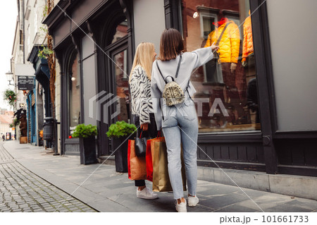 Back view of two women window shopping on the city streets  101661733