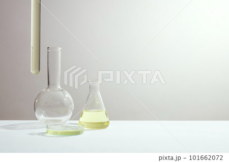 Science and medical background with boiling flask, erlenmeyer flask, petri dish and test tube containing yellow liquid on white background. Space for text and design. 101662072