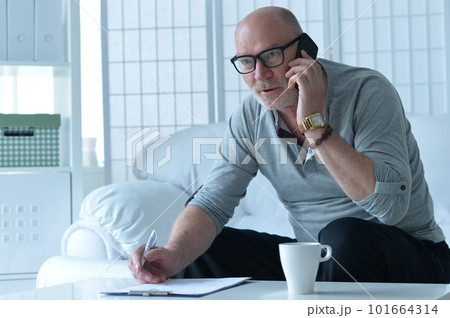 Handsome mature man in eyeglasses sitting and talking on smartphone 101664314