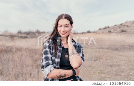 Happy young smiling woman with freckles outdoors portrait. Soft sunny colors. Outdoor close-up portrait of a young brunette woman and looking to the camera, posing against autumn nature background 101664910