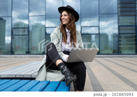 European young woman designer with a laptop in her hands on the background of street buildings 101665093