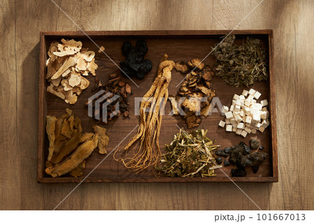 Top view of traditional Chinese herbs placed on a dark wooden tray, on wooden table background. Scene for medicine advertising, photography traditional medicine content 101667013