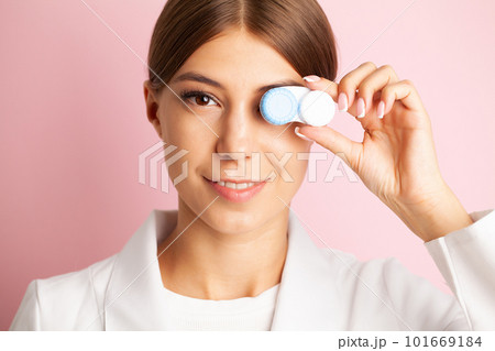 Young woman holding a white container with lenses. 101669184