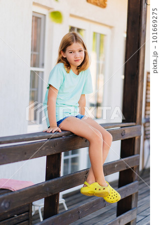 Cute sleepy girl sitting on the railing of the terrace of the house. Cute sleepy girl sitting on the railing of the terrace of the house. 101669275
