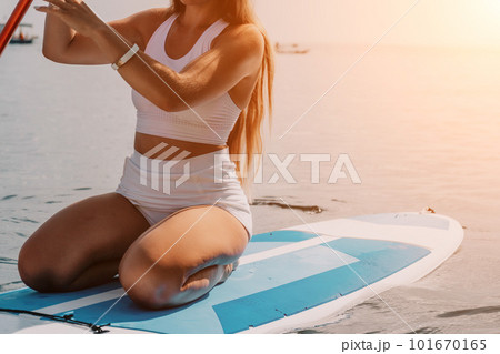 Woman sea sup. Close up portrait of happy young caucasian woman with long hair looking at camera and smiling. Cute woman portrait in bikini posing on sup board in the sea Woman sea sup. Close up portrait of happy young caucasian woman with long hair looking at camera and smiling. Cute woman portrait in bikini posing on sup board in the sea 101670165