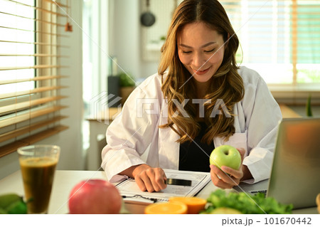 Professional nutritionist working on a diet plan, sitting with different healthy food ingredients in office. Right nutrition, healthy eating Professional nutritionist working on a diet plan, sitting with different healthy food ingredients in office. Right nutrition, healthy eating 101670442