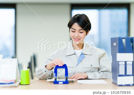 穴あけパンチをする作業服を着たビジネスウーマン 101670930