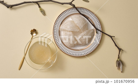 Top view of raw bird nest neatly arranged in round dishes and bowl soup, tree branch on beige background. Healthcare food, popular in Korea, China and Asia 101670956