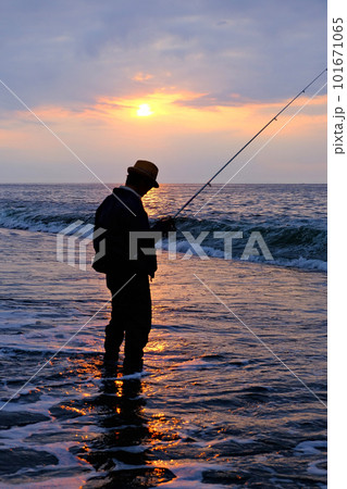 早朝海に入って釣りをする男性のシルエット 101671065