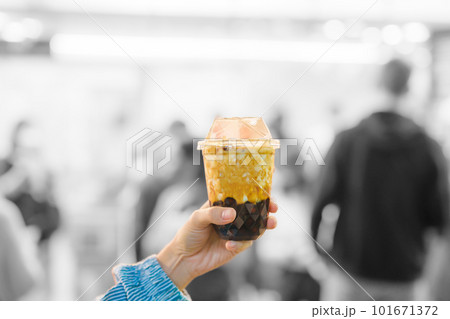 woman hand holding brown sugar boba milk tea with tapioca pearls at night market, famous Taiwanese bubble tea of Taiwan. Street Food and travel in Ximending, Taipei concept 101671372