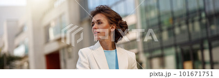 Focused woman in white suit standing near business centre. Blurred background Focused woman in white suit standing near business centre. Blurred background 101671751