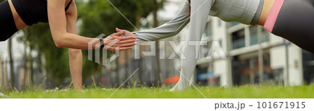 Two happy female friends holding hands while doing plank exercise in park 101671915