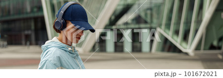 Sportive woman in headphones stands with bottle of water after running in city. Healthy lifestyle 101672021