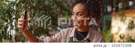 Smiling woman florist taking selfie with her plants for publishing in social media in florar studio Smiling woman florist taking selfie with her plants for publishing in social media in florar studio 101672306