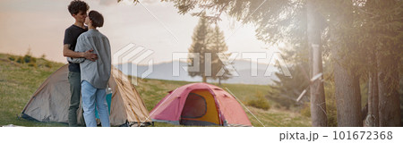 Young couple in love kissing at tents in camping site in mountains. Romantic tour. Young couple in love kissing at tents in camping site in mountains. Romantic tour. 101672368