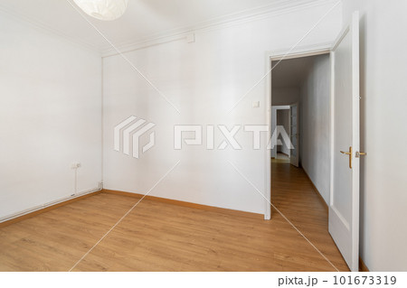 An empty small bright room with white walls and an open door overlooking a corridor in a spacious house. The concept of a room in a hotel or moving. Copyspace An empty small bright room with white walls and an open door overlooking a corridor in a spacious house. The concept of a room in a hotel or moving. Copyspace 101673319