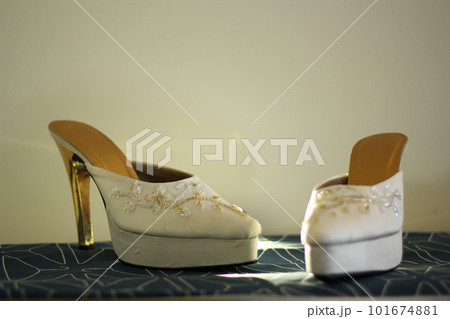 A beautiful pair of white women's high heel shoes embroidered for wedding preparation. A beautiful pair of white women's high heel shoes embroidered for wedding preparation. 101674881