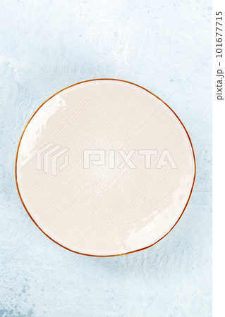 An empty white plate with a gold rim, top shot on a slate background 101677715