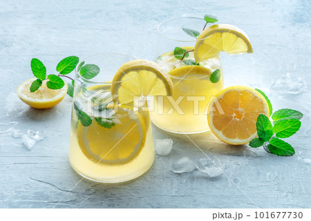 Lemonade with mint. Lemon water drink with ice. Two glasses and lemons Lemonade with mint. Lemon water drink with ice. Two glasses and lemons 101677730