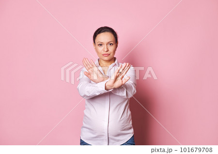 Middle aged confident pregnant woman standing with outstretched hand showing stop sign, crossing arms, looking at camera, preventing you, expressing denial and refusal over isolated pink background Middle aged confident pregnant woman standing with outstretched hand showing stop sign, crossing arms, looking at camera, preventing you, expressing denial and refusal over isolated pink background 101679708